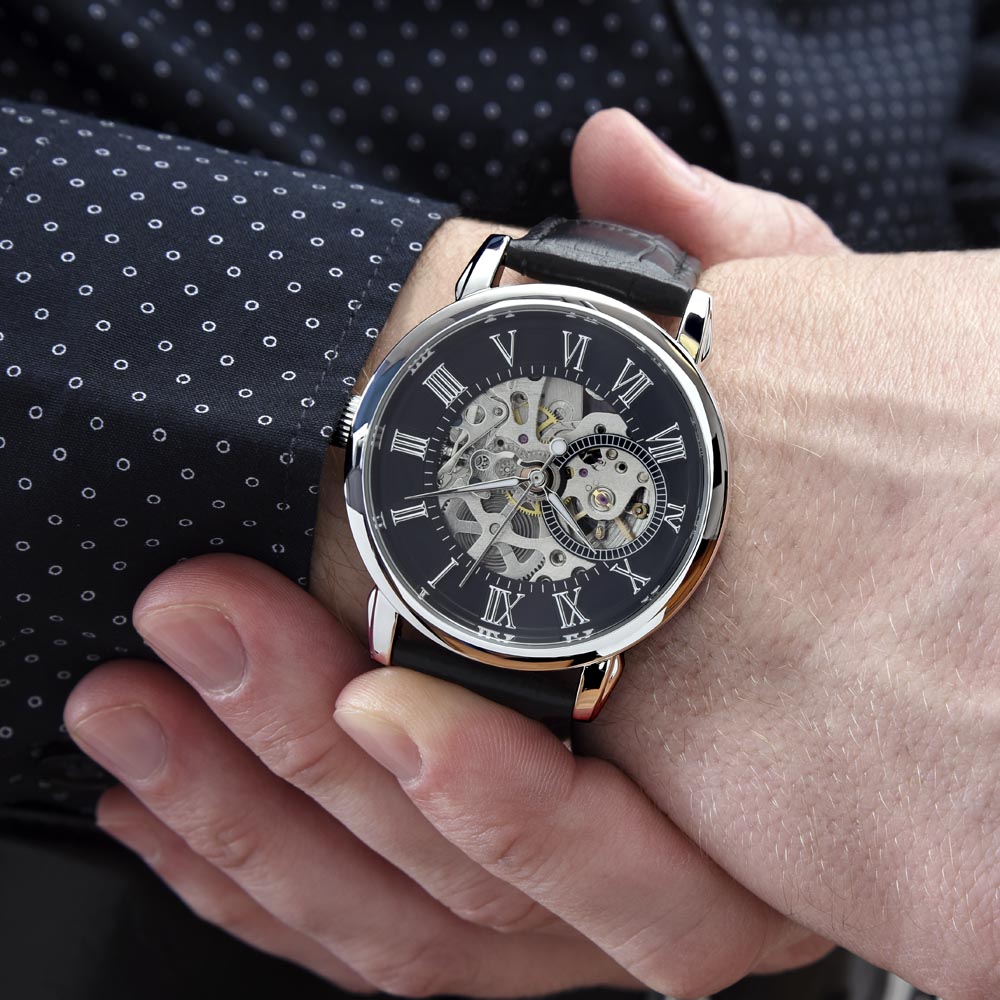 Skeleton watch on wrist with black leather strap and silver round case, roman numerals