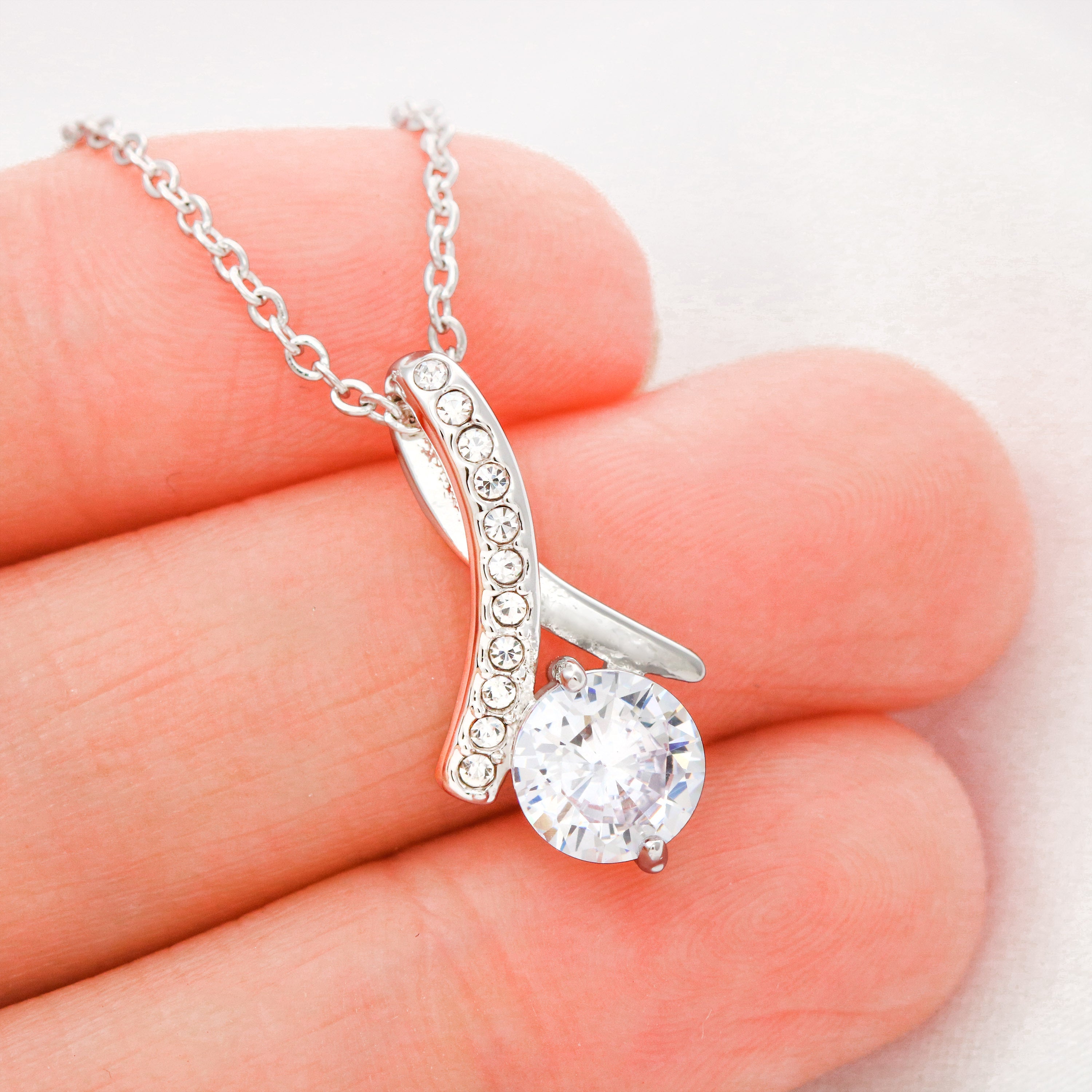 Silver-tone necklace close-up: teardrop pendant with round sparkling stone and pavé