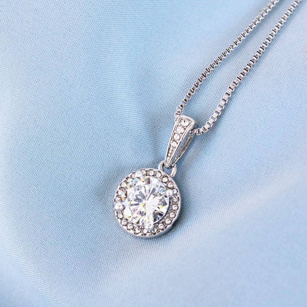 Silver-tone round halo cubic zirconia pendant on fine link chain, close-up