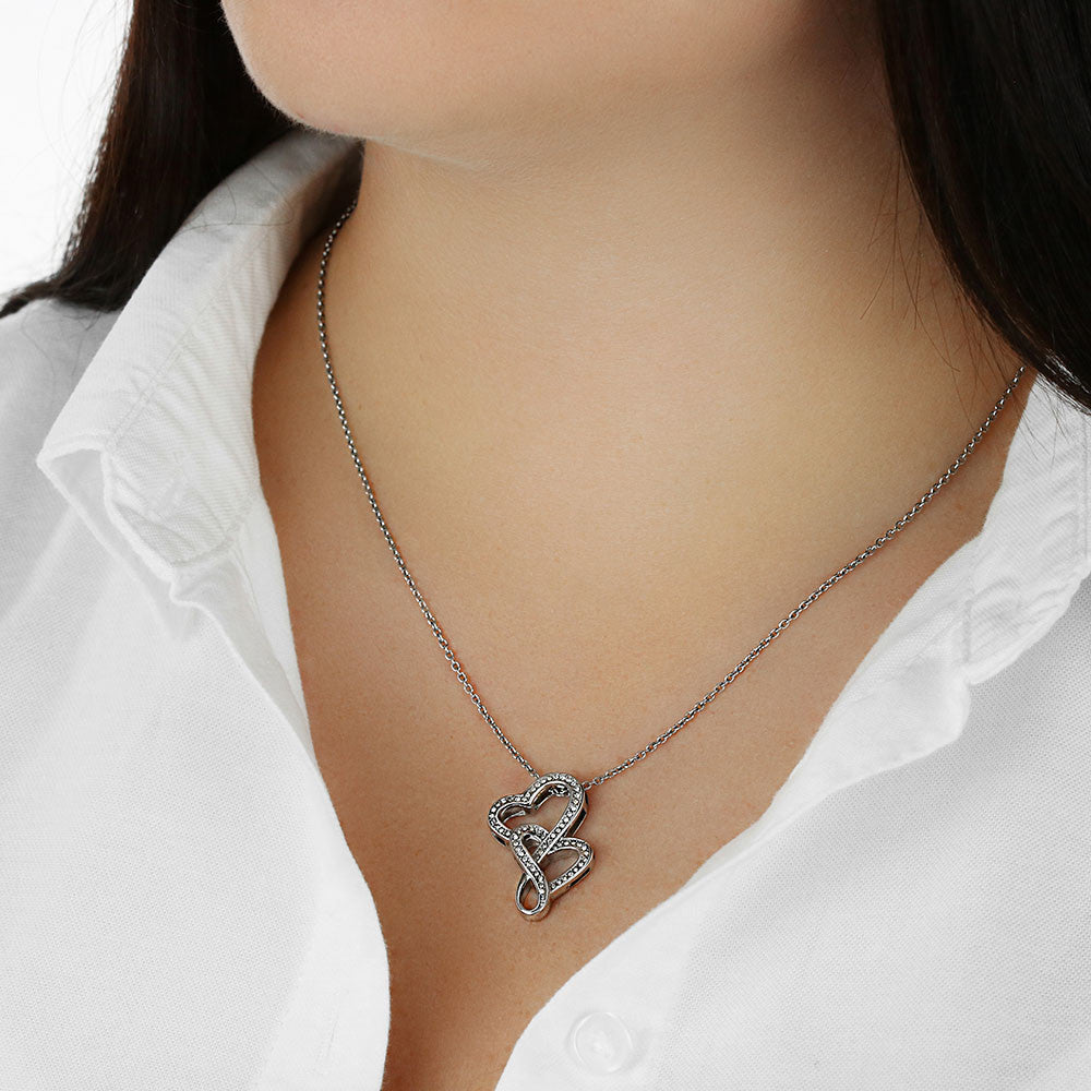 Silver-tone heart pendant necklace on neck, worn with white collared top