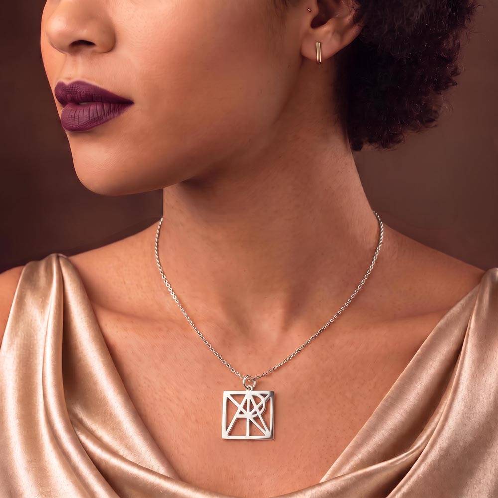 Silver-tone monogram name necklace pendant on chain, worn with satin dress