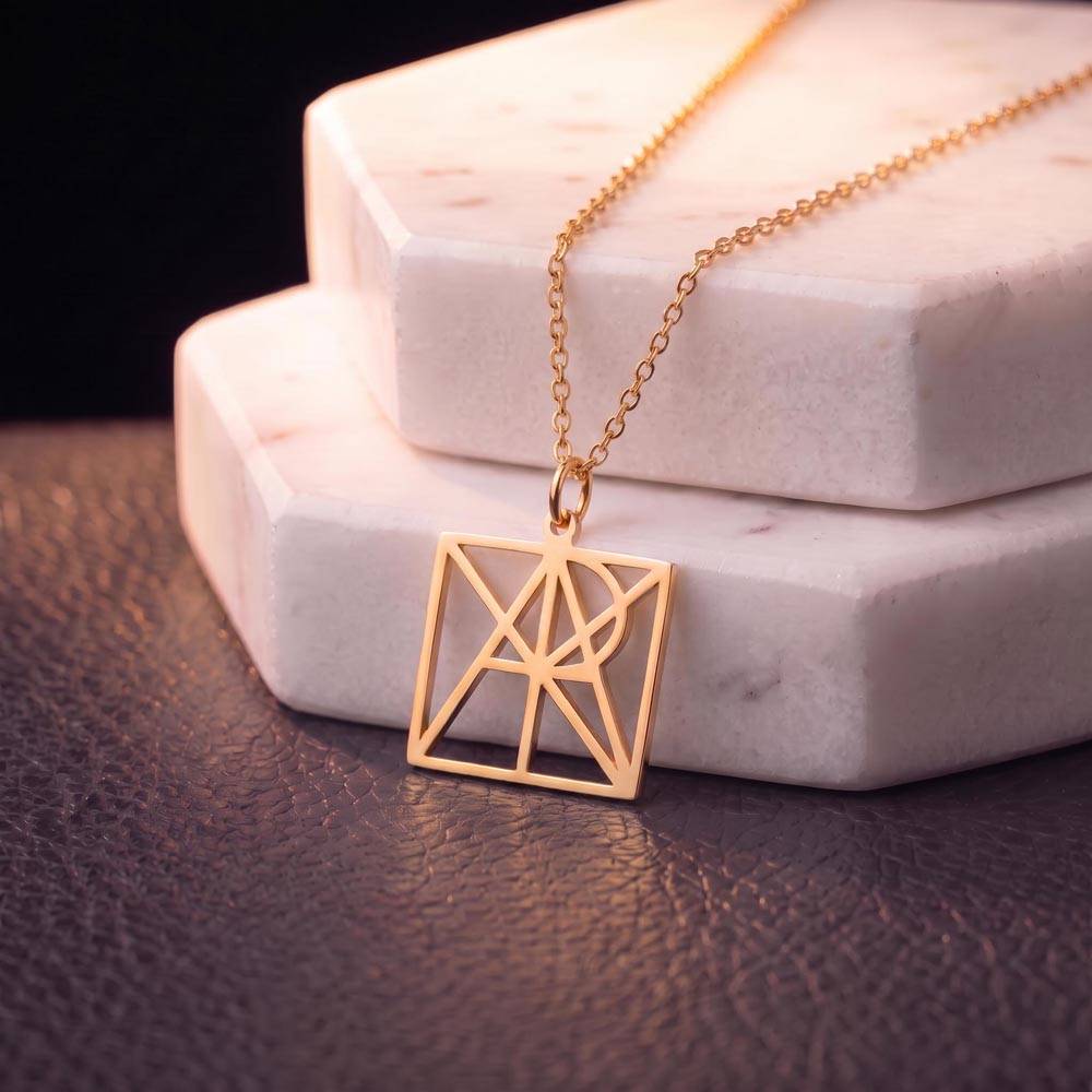 Close-up of gold-tone monogram name pendant on a chain