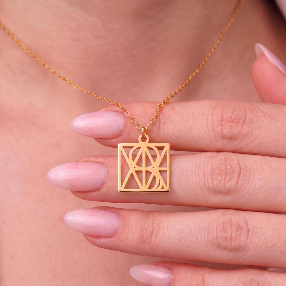 Gold-tone personalized monogram name necklace pendant held in fingers