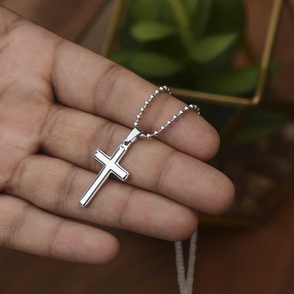 Silver cross pendant necklace with beaded chain held in a hand