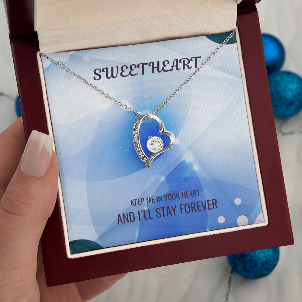 Silver heart pendant necklace in red gift box, held in hand, message card