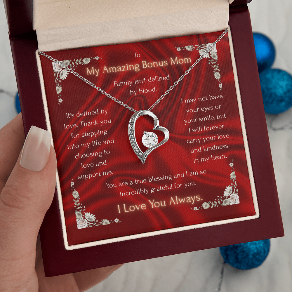 Silver heart pendant necklace on red floral card held in gift box, small chain visible.