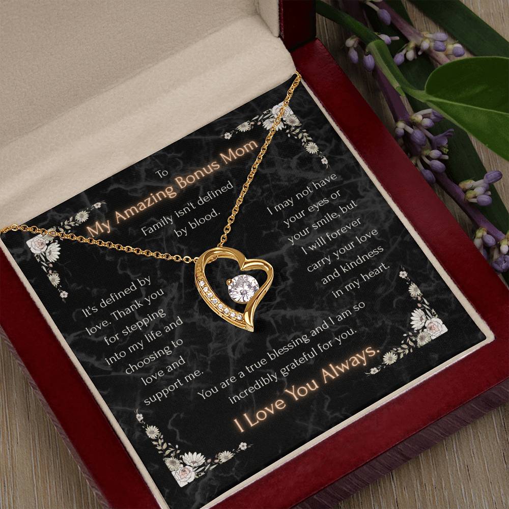 Gold-tone heart pendant necklace over black floral message card in a maroon gift box
