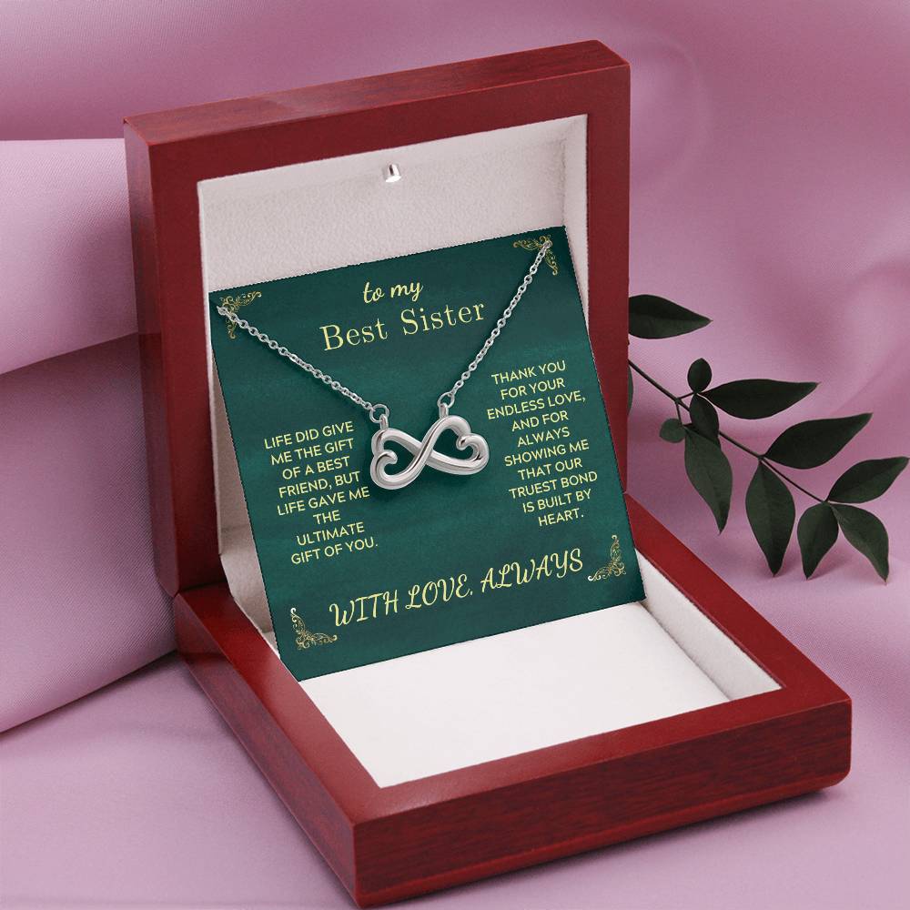 Heart infinity necklace in a green card box shown in an open wooden gift case.