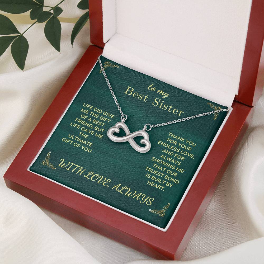 Open red gift box holding a green card with silver heart infinity pendant necklace.