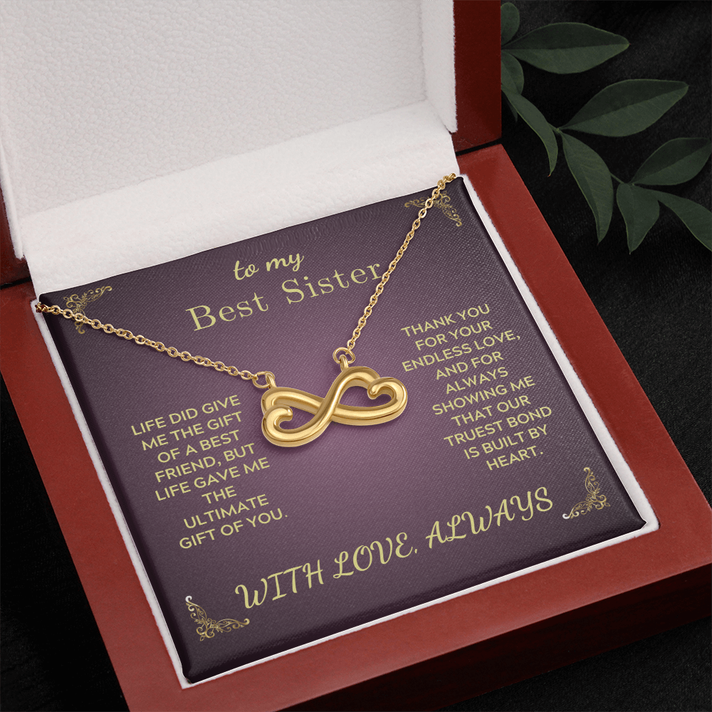 Gold heart-and-infinity pendant necklace on purple insert inside red box