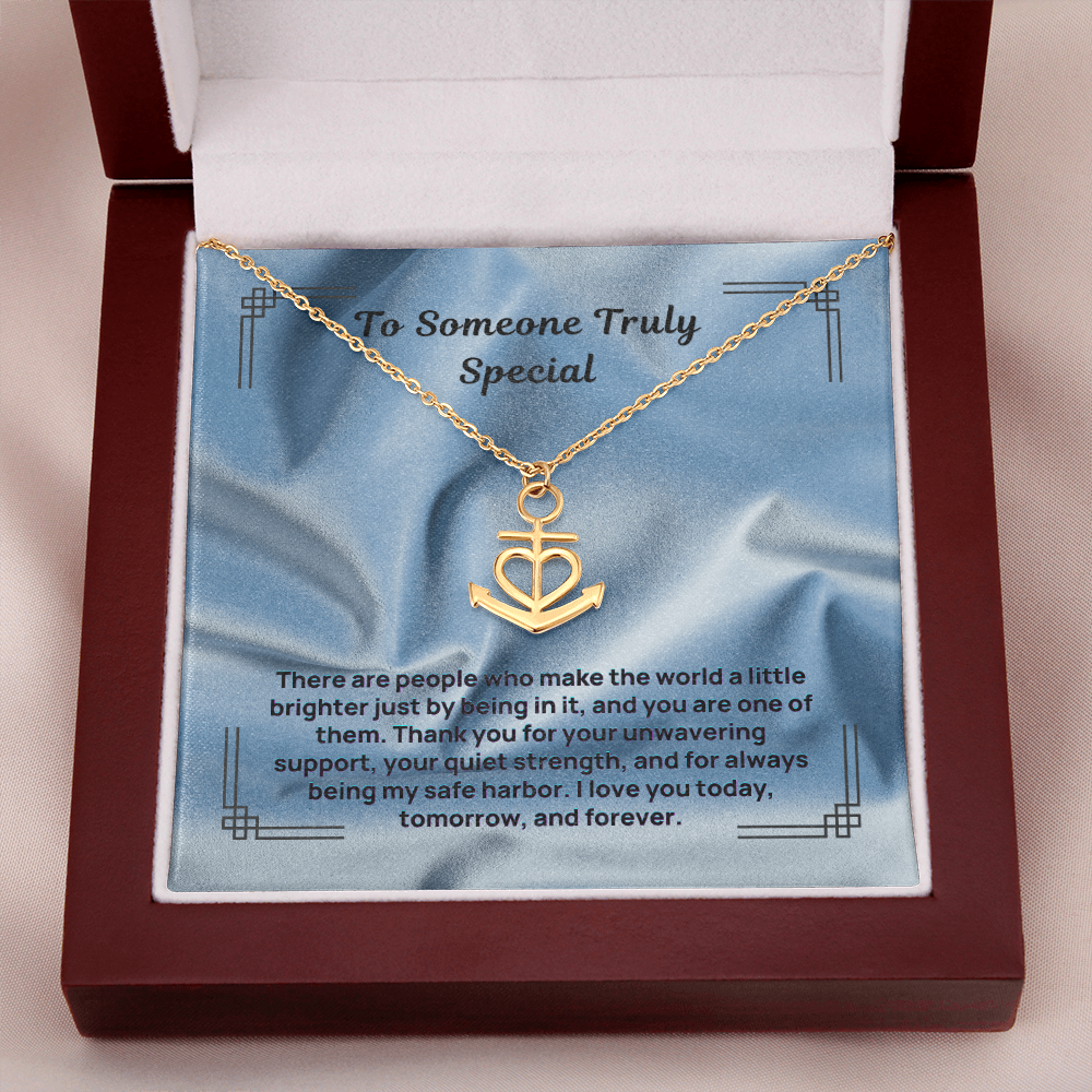 Gold anchor and heart pendant necklace on a chain inside a gift box.