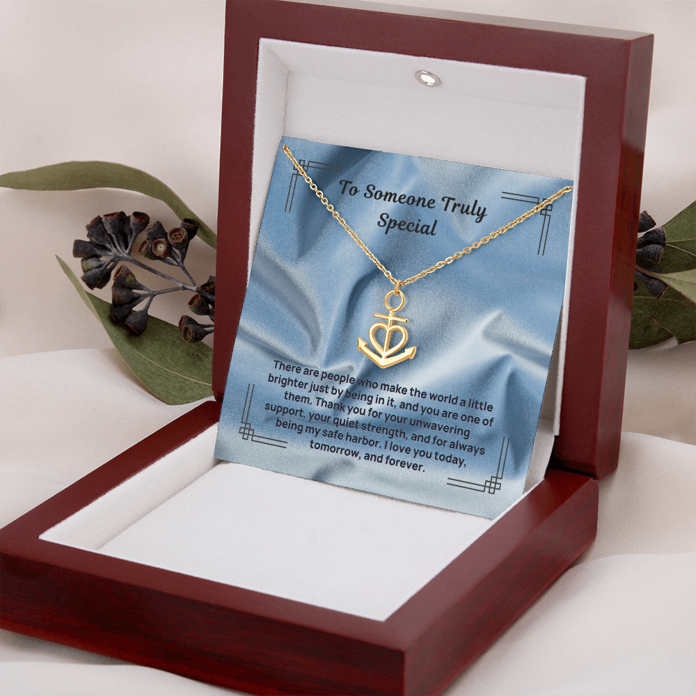 Gold anchor and heart pendant necklace with a linked chain inside a wooden gift box.
