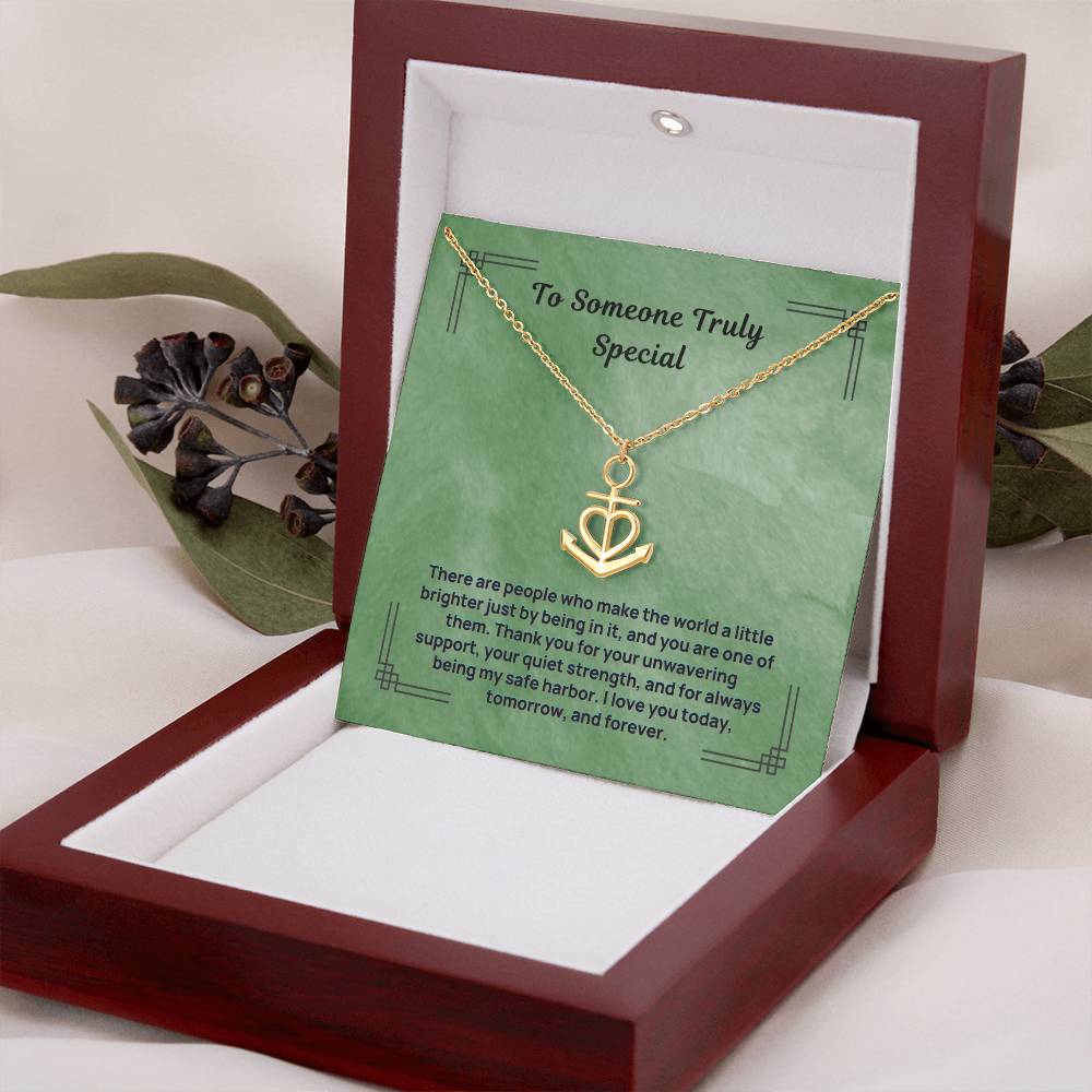 Gold anchor safe harbor pendant necklace resting on green card