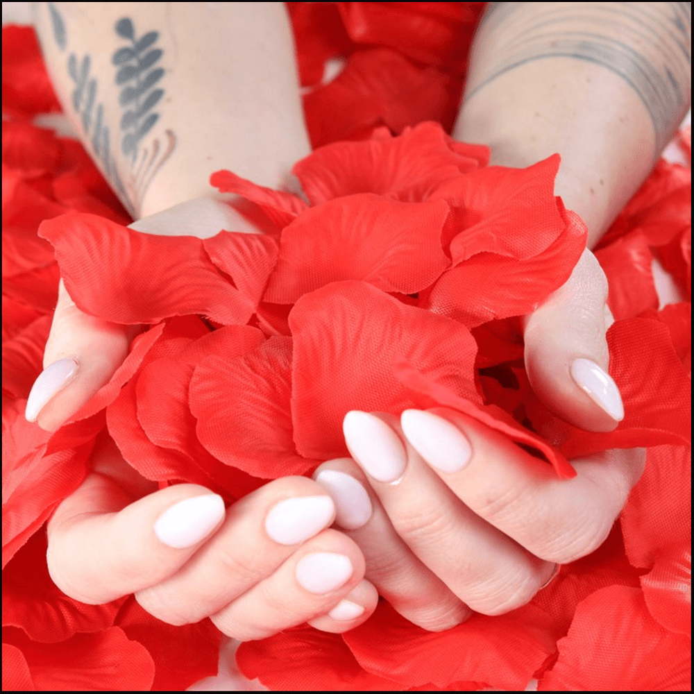 Red rose petals with hands cupping the petals, soft fabric texture