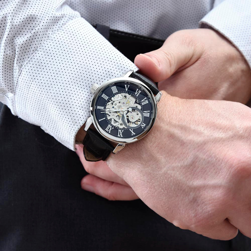 Open-work wristwatch on wrist with black leather strap; silver case and black dial