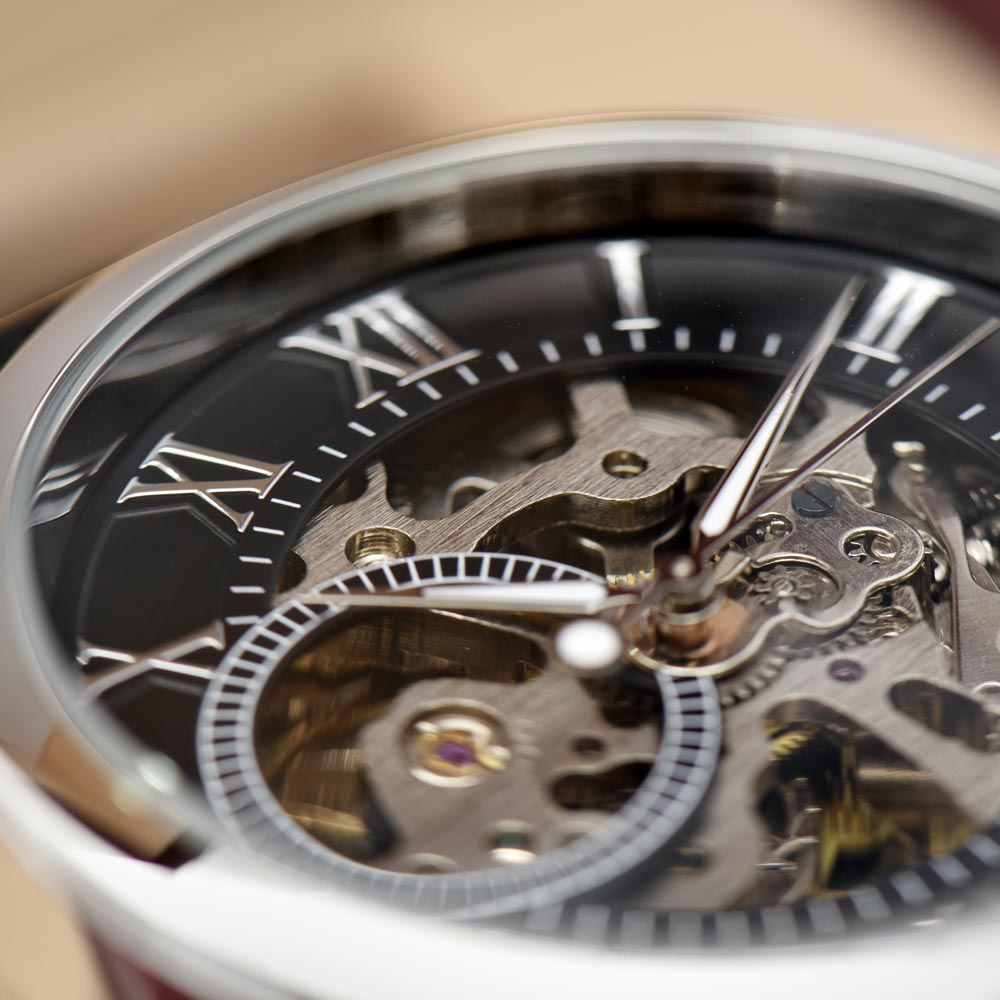 Close-up of open-work black watch dial with roman numerals and exposed movement