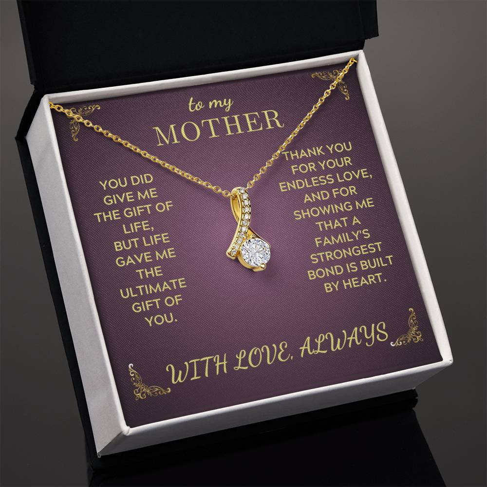 Gold-tone pendant necklace with teardrop heart charm inside open purple gift box