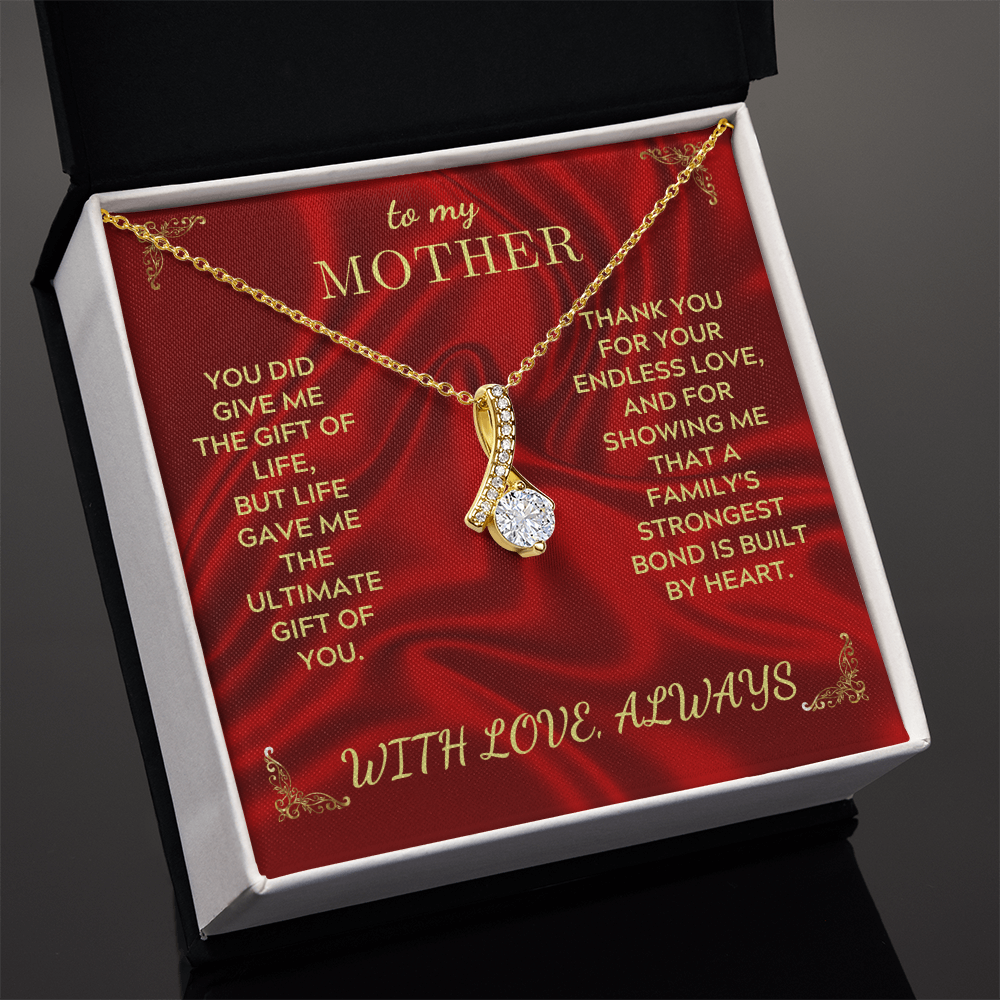 Gold-tone necklace with teardrop crystal heart pendant inside open red gift box