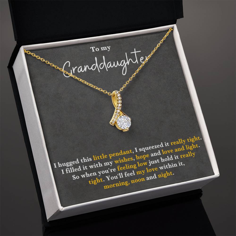 Gold-tone pendant necklace displayed in an open box, with teardrop charm pendant.