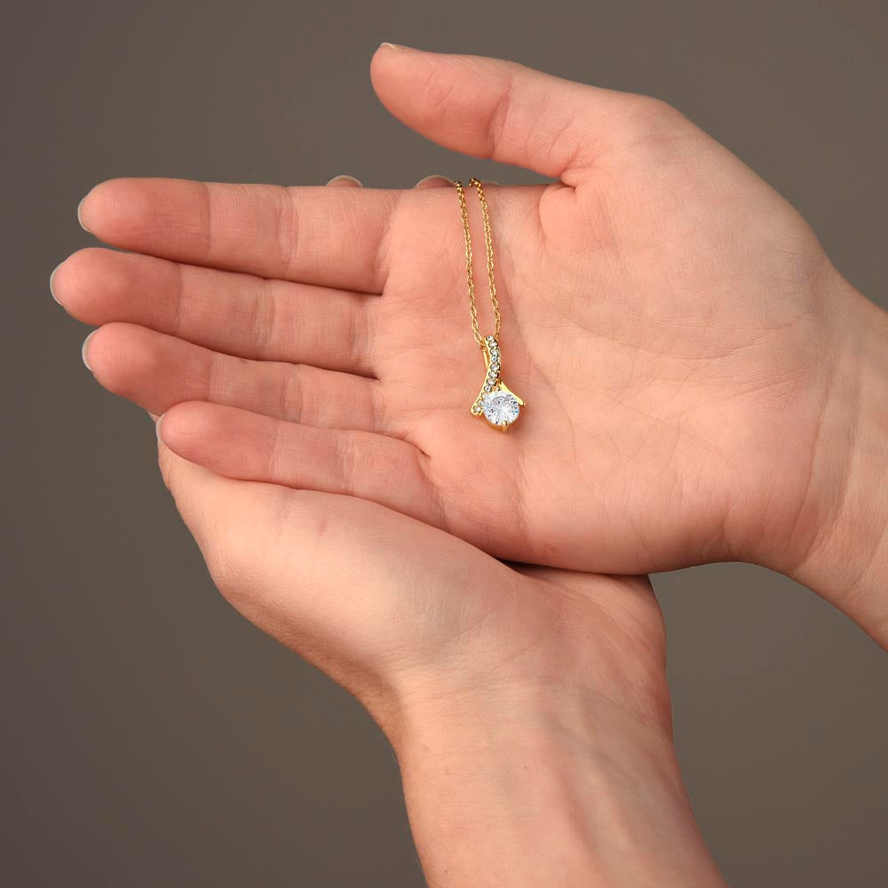 Gold-tone delicate chain necklace with small crystal heart pendant in open palm