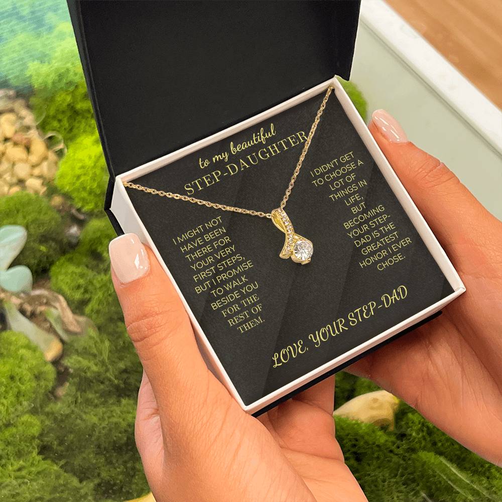 Gold-tone pendant necklace with round stone drop charm held in gift box outdoors
