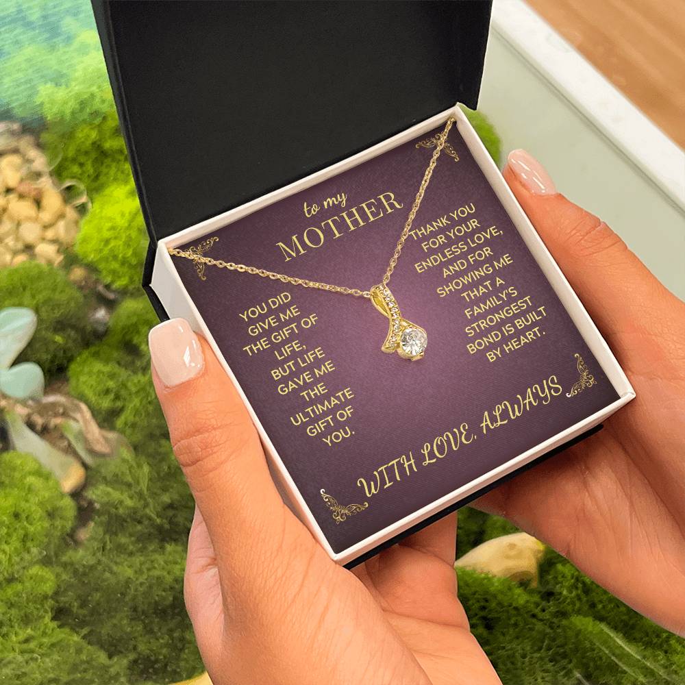 Gold-tone teardrop pendant necklace in a purple gift box held outdoors