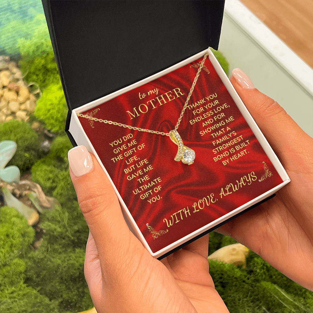 Gold necklace with teardrop heart pendant in red gift box held by hands