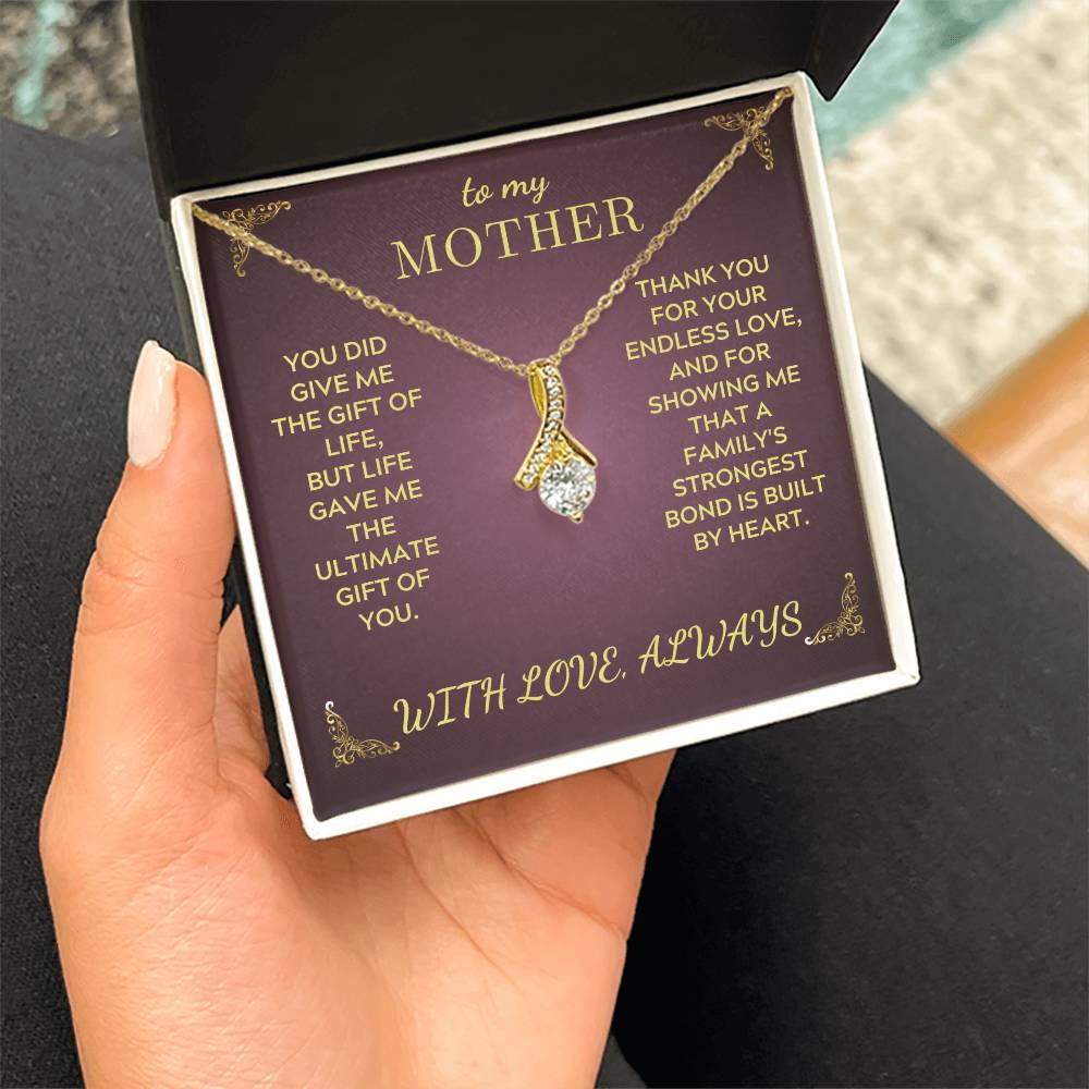 Gold-tone teardrop pendant necklace in a purple gift box held in a hand