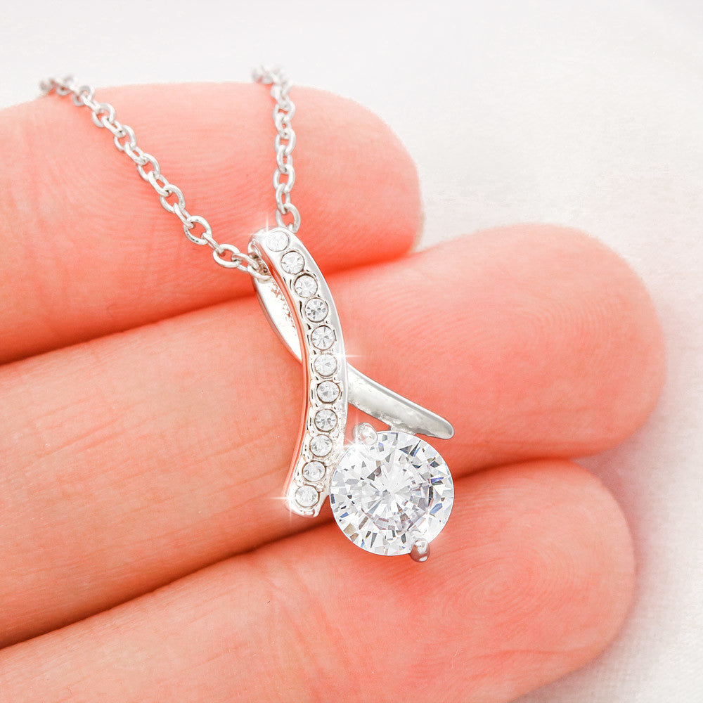 Silver-tone necklace with teardrop crystal pendant, close-up on hand.