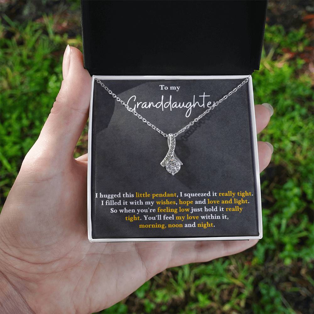 Silver-tone pendant necklace held in hand, featuring a teardrop charm with sparkle stones.