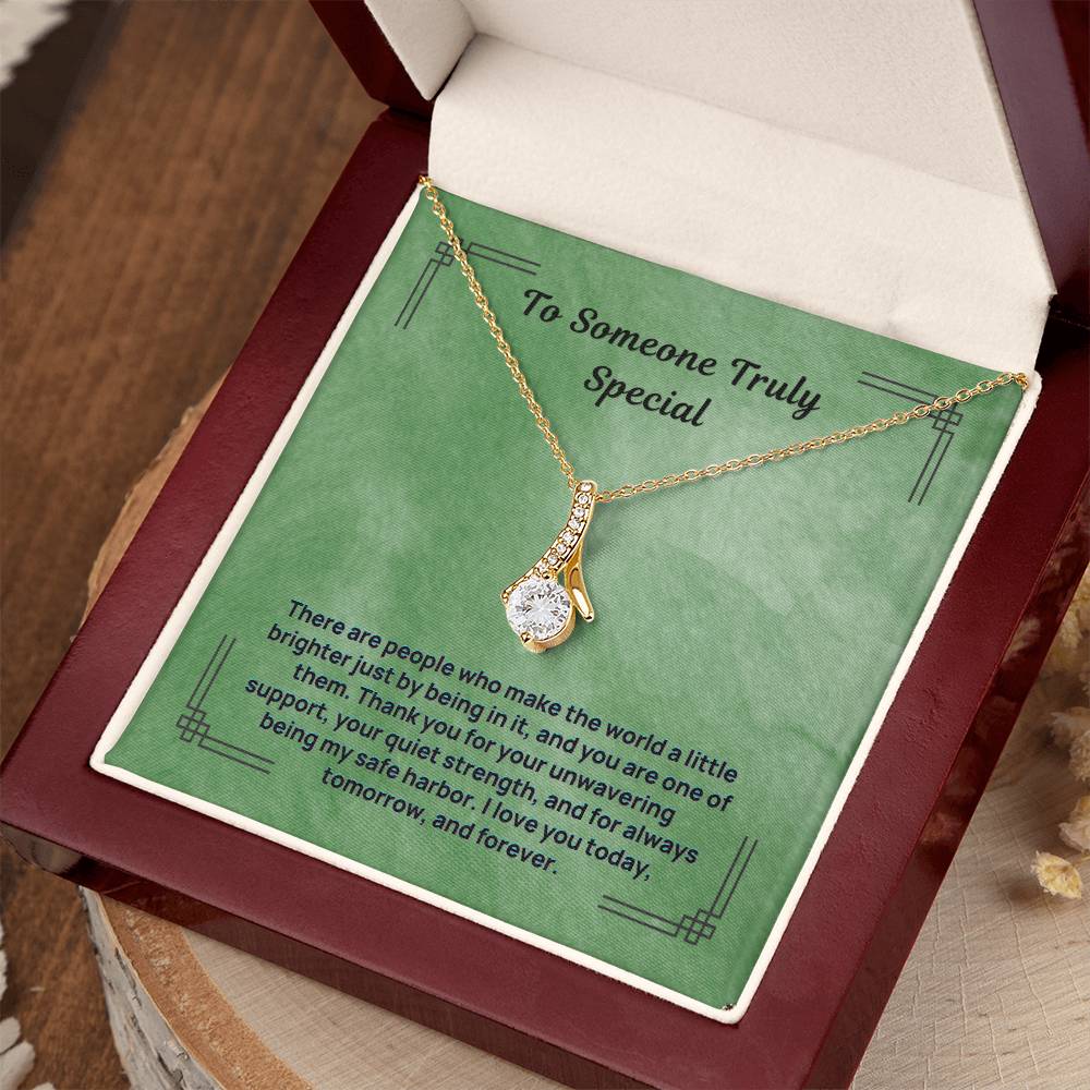 Green message necklace with gold-tone chain and teardrop pendant, displayed in open box