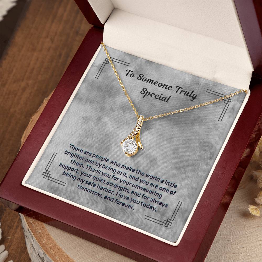 Gold-tone necklace with teardrop pendant on grey insert inside red gift box