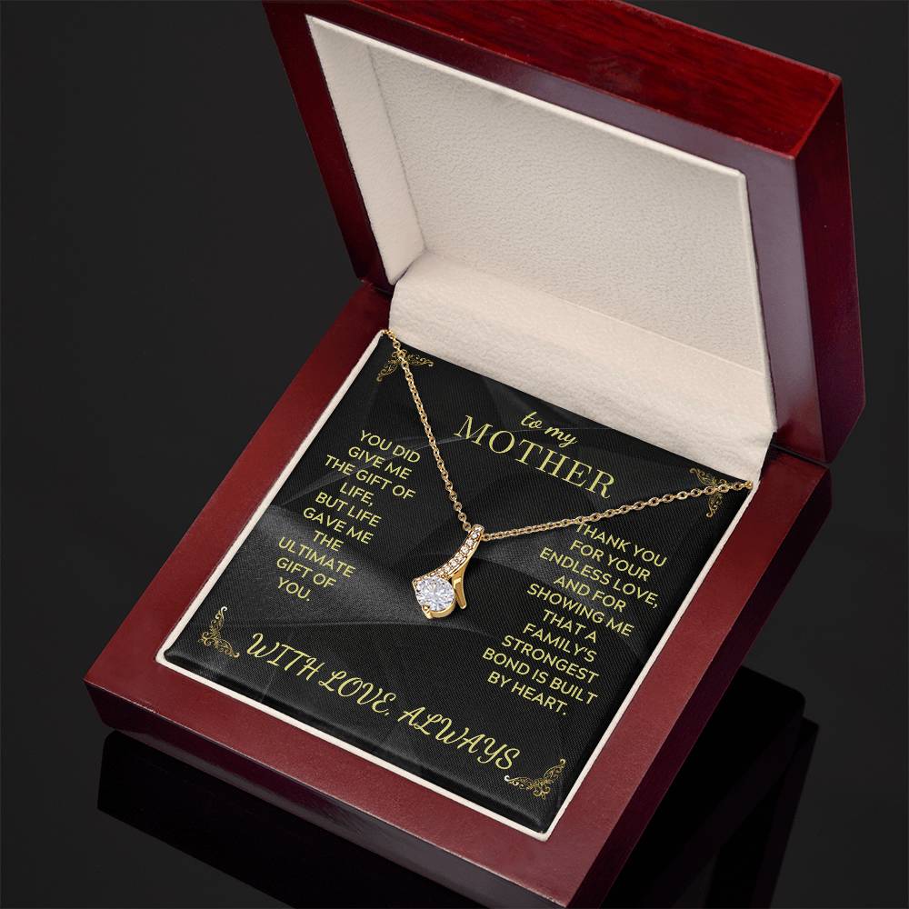 Gold-tone teardrop pendant necklace with rhinestone cluster shown on black card in red box