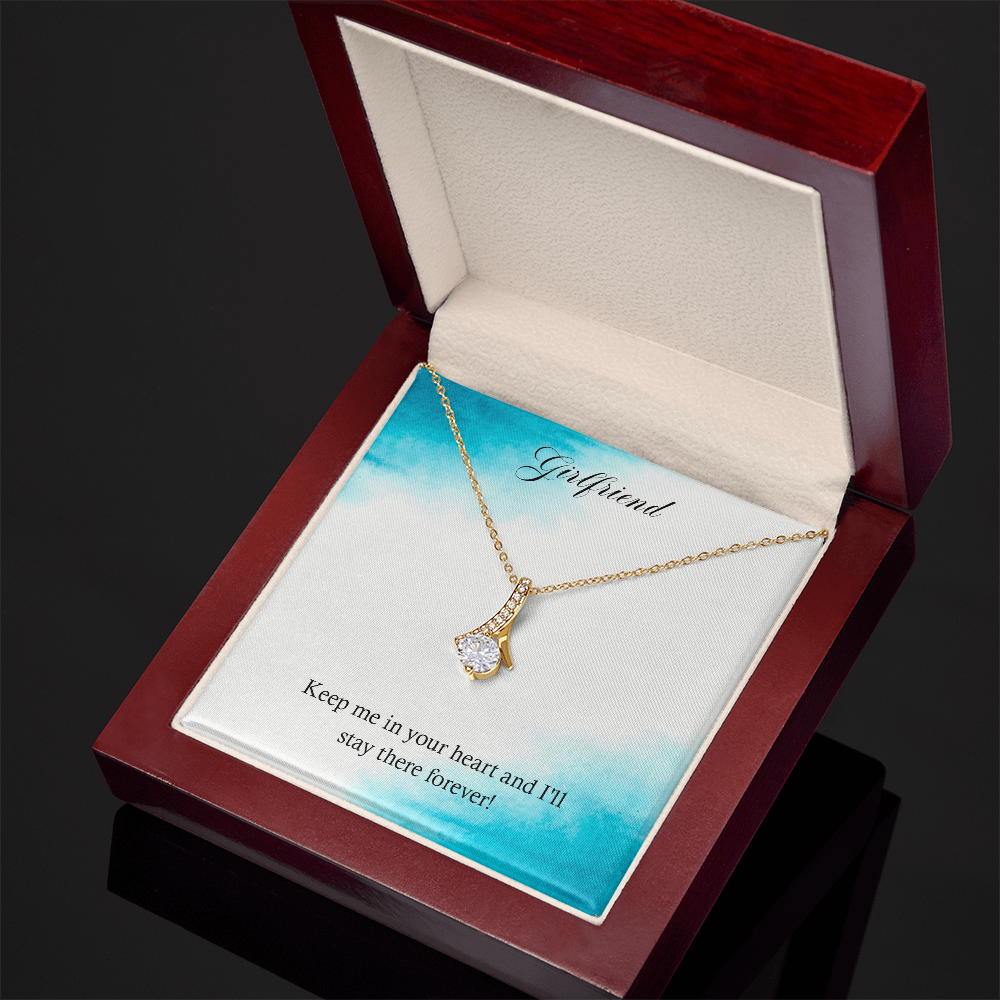 Gold-tone heart teardrop pendant necklace laid on a jewelry box cushion.