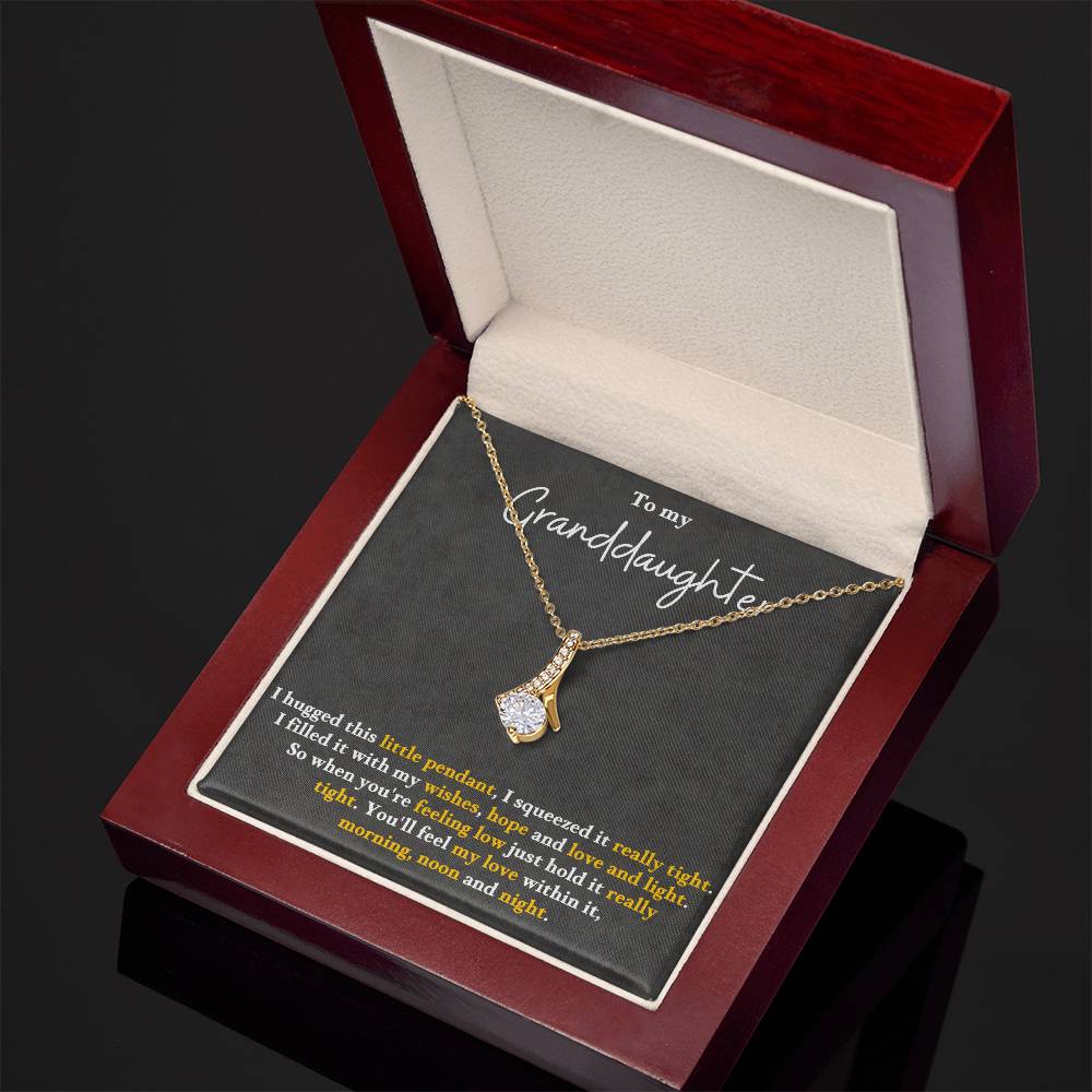 Gold-tone pendant necklace in an open red gift box, with teardrop charm pendant.
