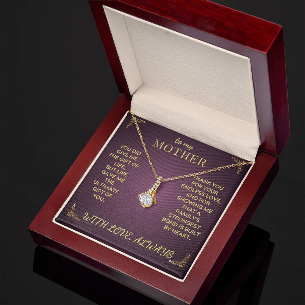Gold-tone pendant necklace with teardrop heart charm on open red jewelry gift box