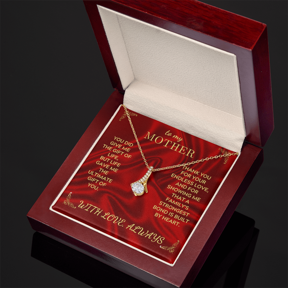Gold-tone teardrop crystal heart pendant necklace resting in open red gift box