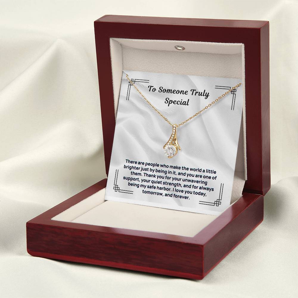 Gold tone pendant necklace inside burgundy hinged gift box with message card