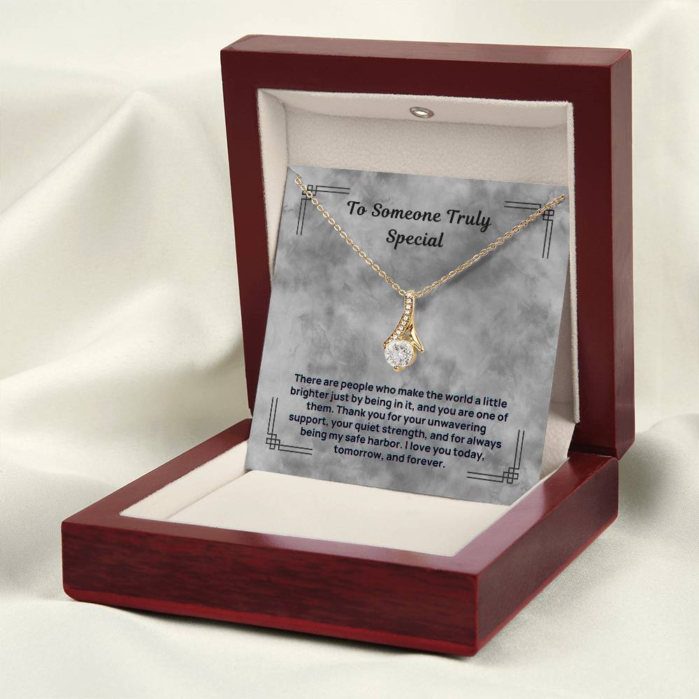 Gold-tone necklace with teardrop pendant resting in open maroon display box