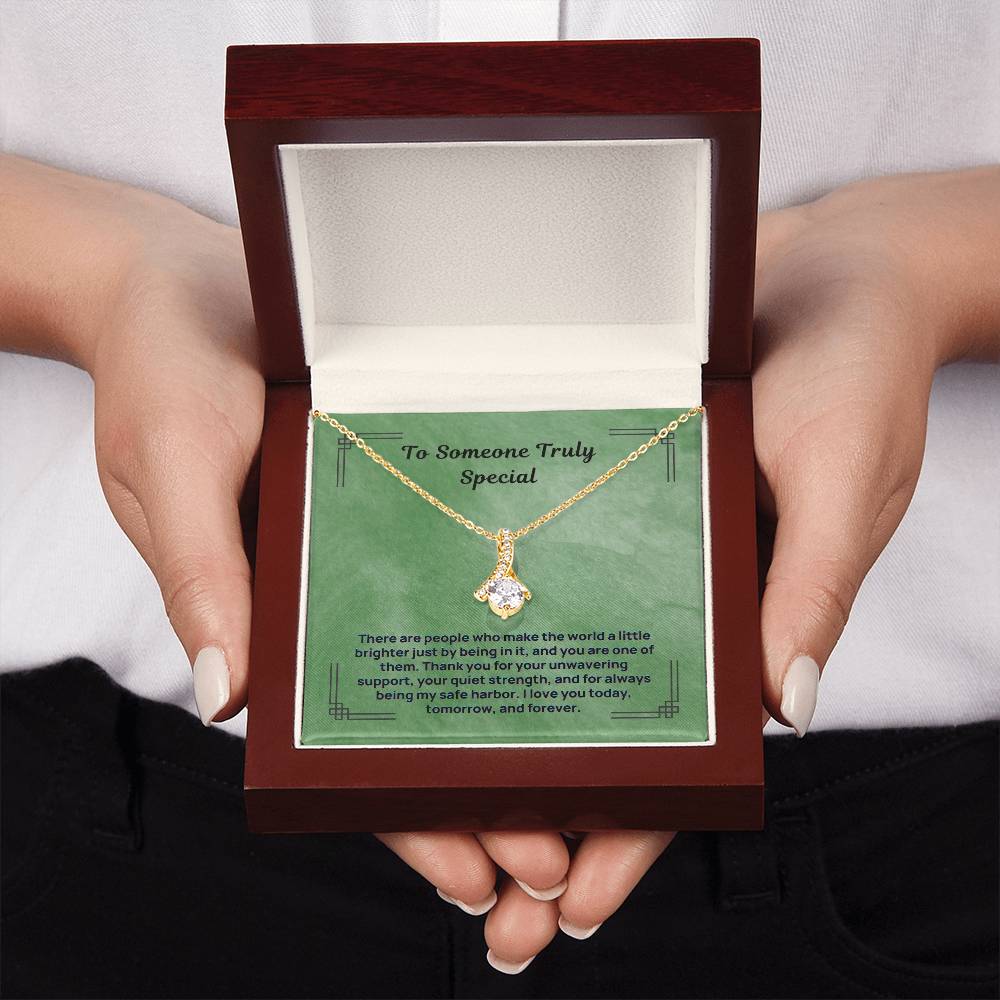 Green gift box with gold-tone message necklace and teardrop pendant, held in hands