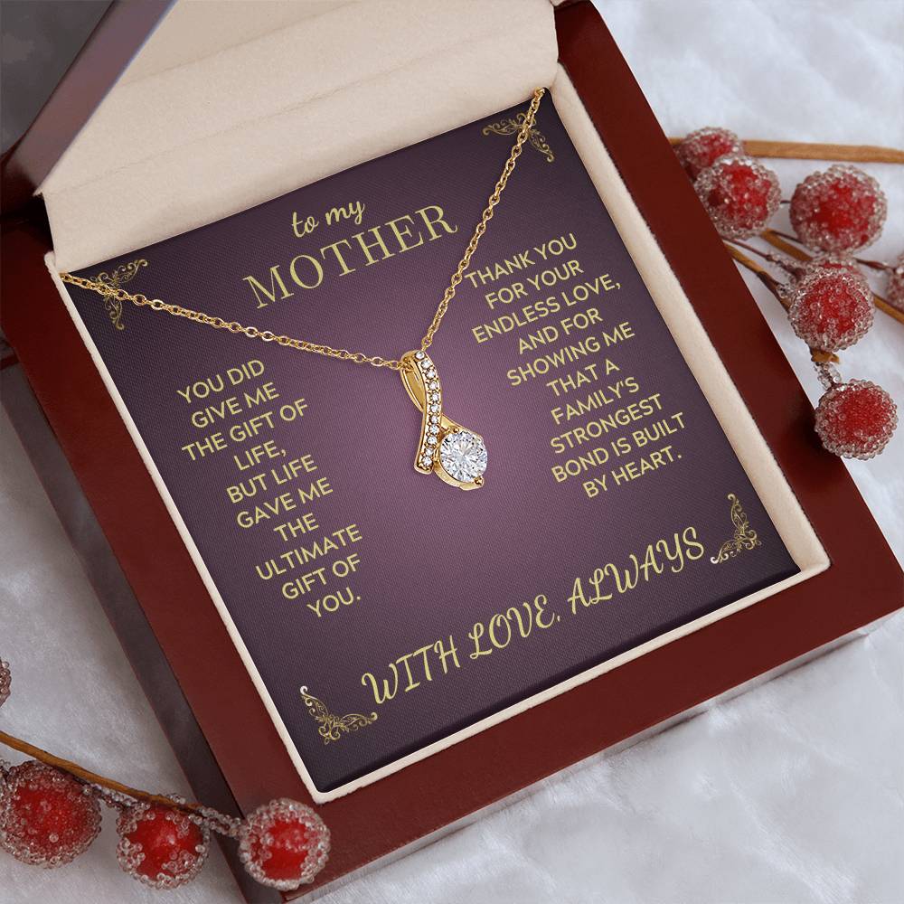 Jewelry necklace displayed on purple insert inside open gift box, gold-tone teardrop crystal pendant