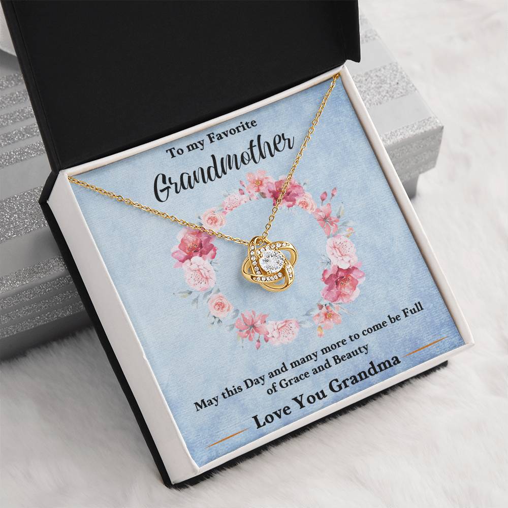 Gold-tone love knot heart pendant necklace in a blue gift box on white fur
