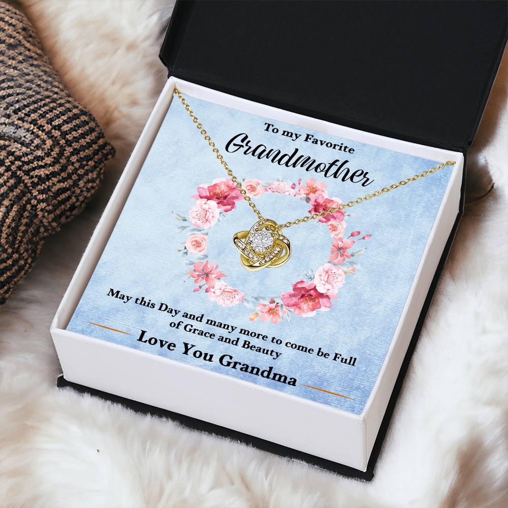 Gold-tone love knot heart pendant necklace displayed on a blue gift card