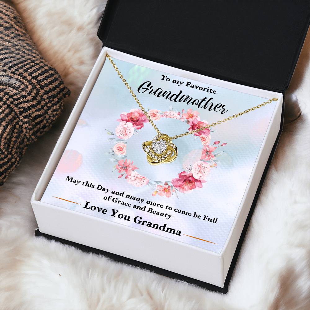 Gold-tone heart love knot necklace pendant with chain in a gift box on white fur