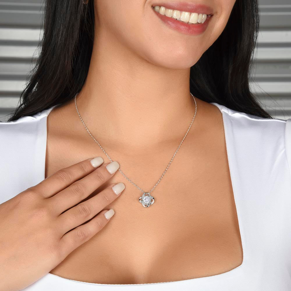 Silver love knot necklace with round knot pendant worn at collar