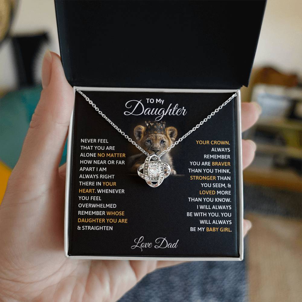 Silver-tone crown pendant necklace on black gift box insert held in a hand