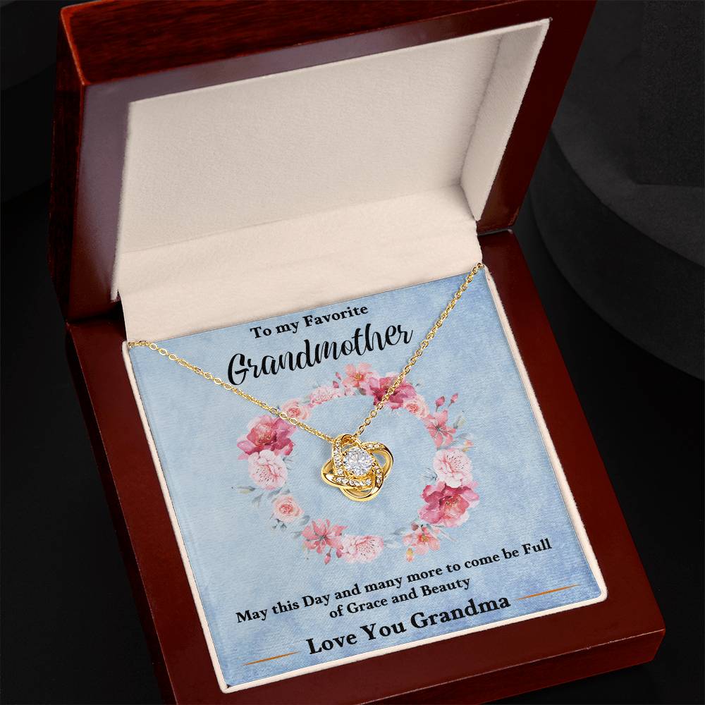 Gold-tone love knot heart pendant necklace on a blue gift card inside a box