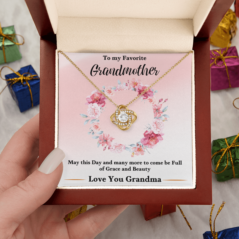 Gold love-knot pendant necklace in pink floral keepsake box held by hand