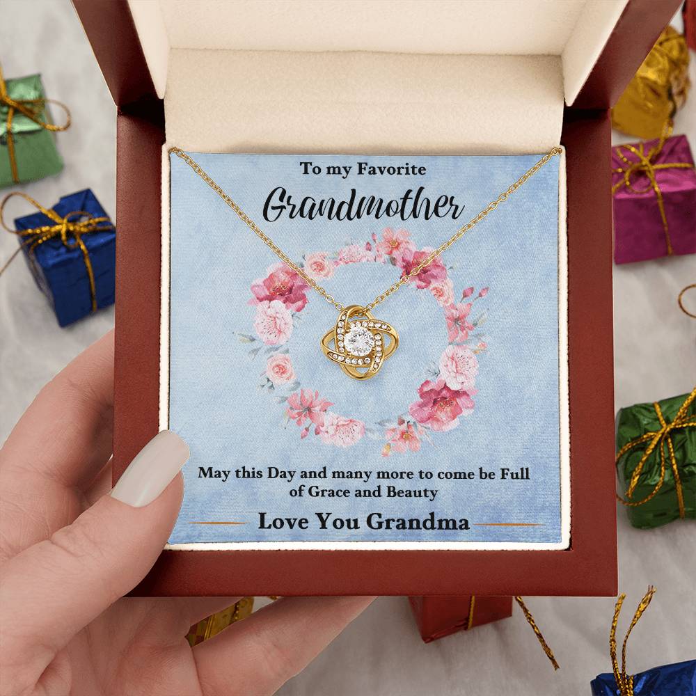 Gold-tone heart love knot pendant necklace on a blue gift card inside a box
