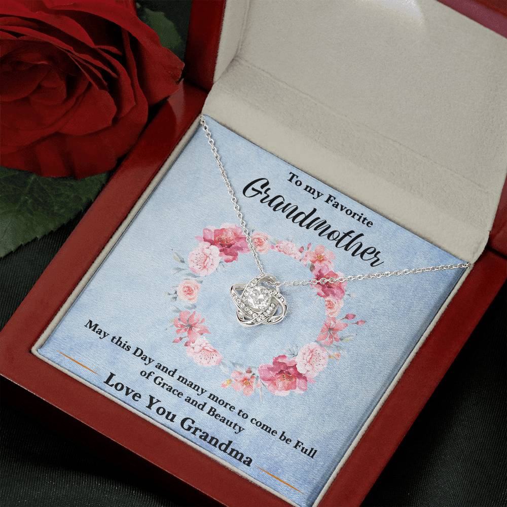 Silver-tone heart love knot pendant necklace resting in a blue gift box